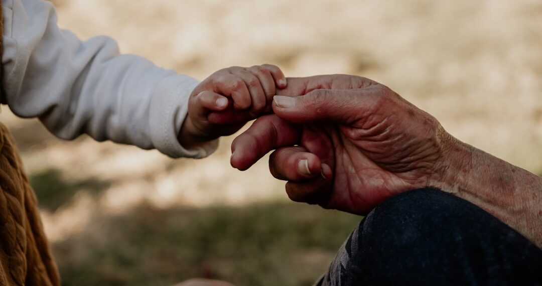 A grandmother and her grand child connecting through holding hands, the difference in age symbolic and heart touching.