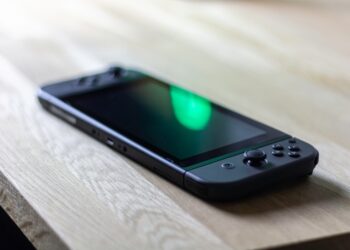 Nintendo Switch in black lying on my desk with a green reflection at the display