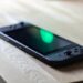 Nintendo Switch in black lying on my desk with a green reflection at the display