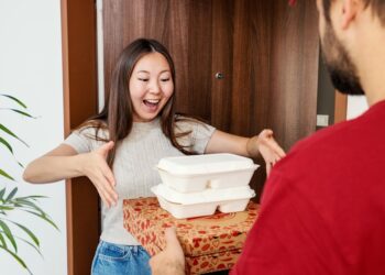 Excited Woman Receiving Food Delivery at Home Door from Courier
