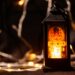 A lit black Ramadan lantern with a mosque design stands against a background of warm bokeh fairy lights.