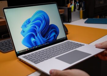 Windows laptop open on modern desk with blue wallpaper