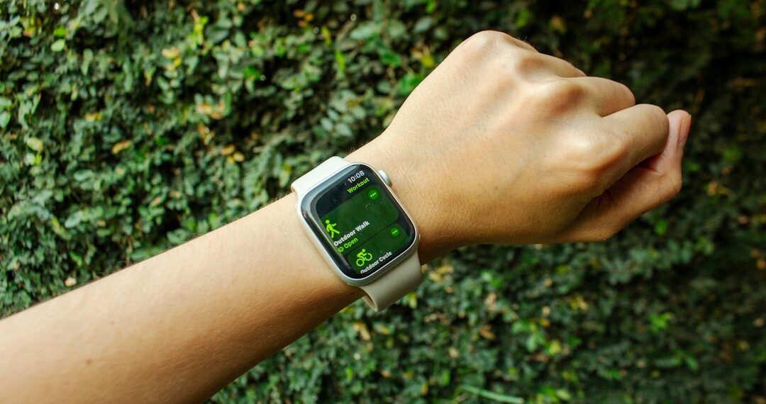 A hand with an Apple Watch about to start an outdoor walk workout, surrounded by nature and natural light.