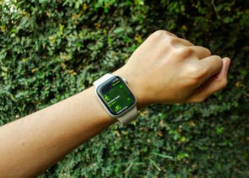 A hand with an Apple Watch about to start an outdoor walk workout, surrounded by nature and natural light.