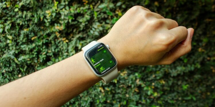 A hand with an Apple Watch about to start an outdoor walk workout, surrounded by nature and natural light.