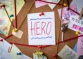 Hero search concept. Close-up view of a detective board with evidence. In the center is a white sheet attached with a red pin with the text Hero.