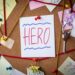 Hero search concept. Close-up view of a detective board with evidence. In the center is a white sheet attached with a red pin with the text Hero.