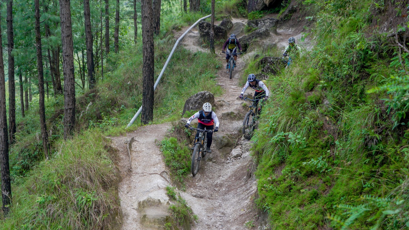 Mountainbikers dalen af op een steile boomrijke trail