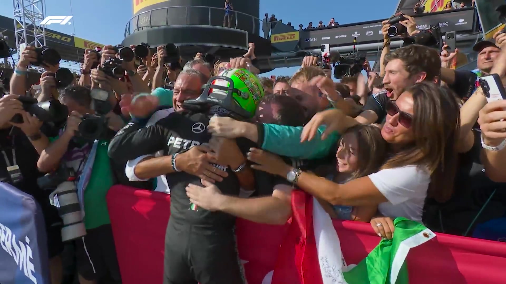 Kimi Antonelli in zijn Mercedes-pak wordt omhelsd door het team na zijn zege in Monza