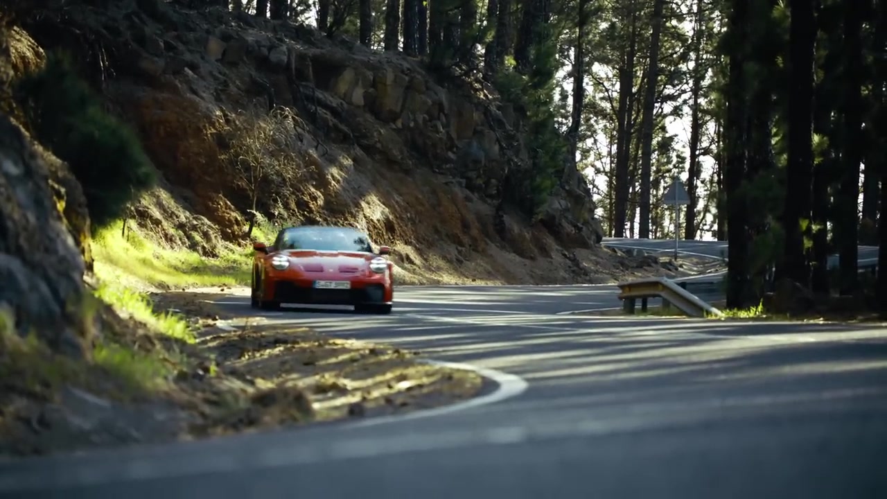 Een rode Porsche 911 GT3 S/C met open dak op een bochtige bergweg