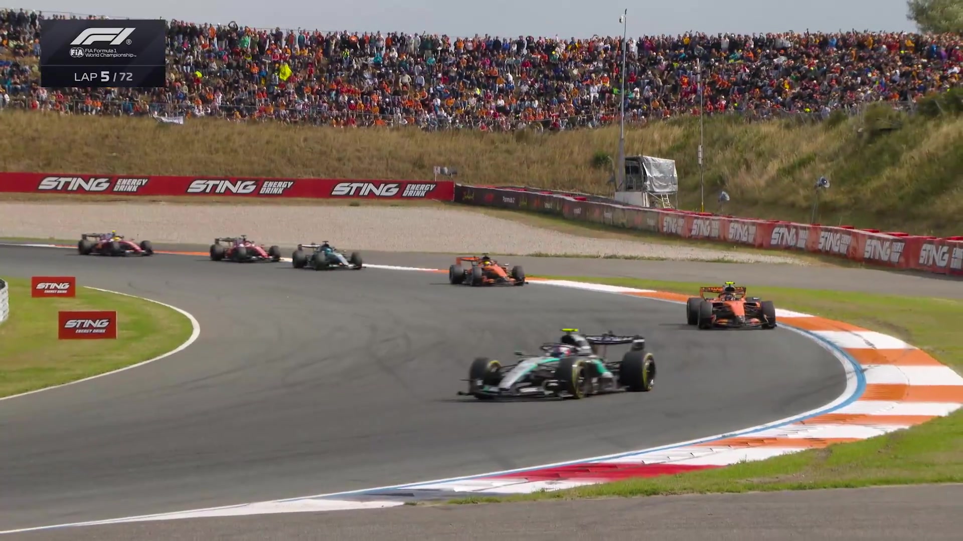 Formule 1-auto's rijden door een bocht op het circuit van Zandvoort met volle tribunes tijdens de Dutch Grand Prix 2026