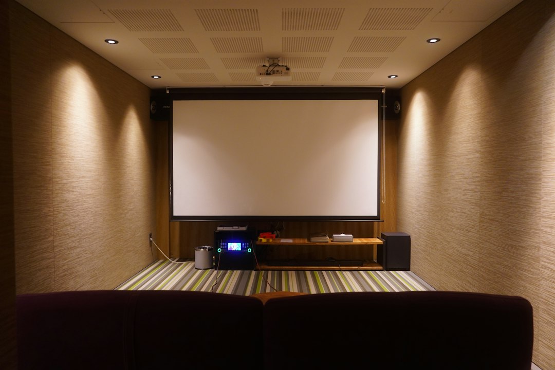 Thuisbioscoop met projectiescherm, stoffen wandbekleding en een brede bank