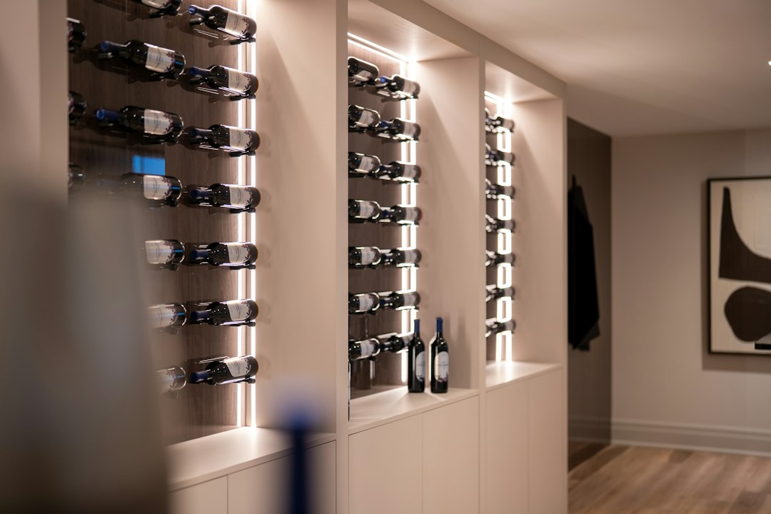 Moderne wijnwand met verlichte flessenrekken in een lichte woning