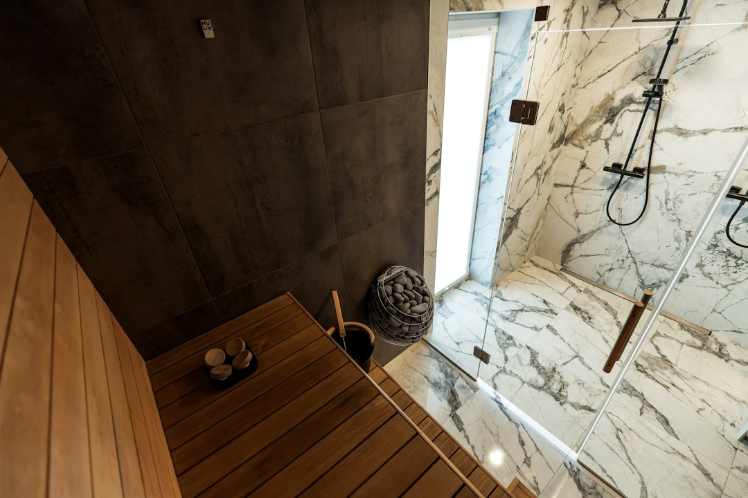 Moderne badkamer met een houten saunabank naast een inloopdouche met marmeren tegels