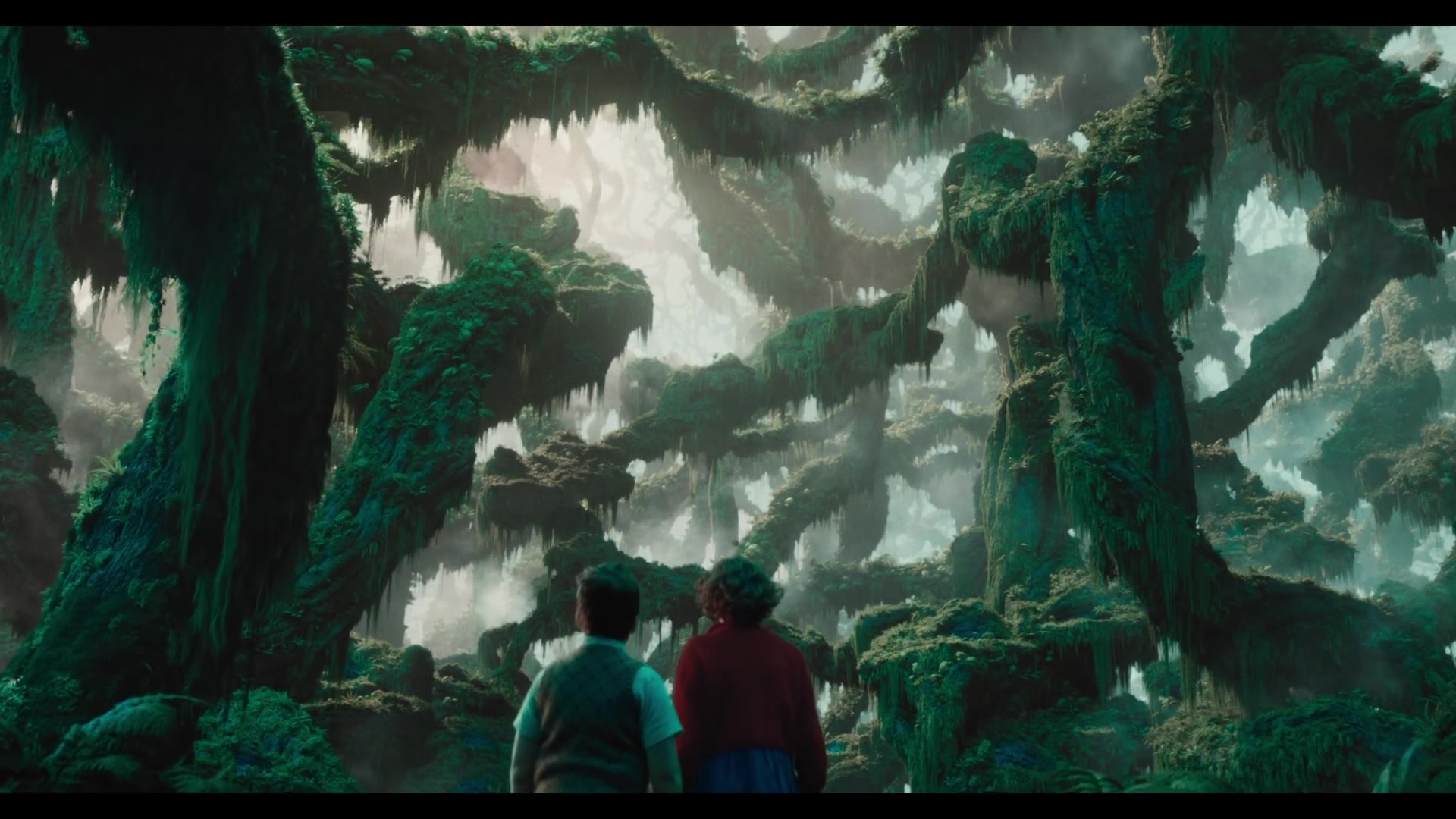 Digory en Polly staan in een bos van reusachtige bemoste bomen in de trailer van Narnia The Magician's Nephew