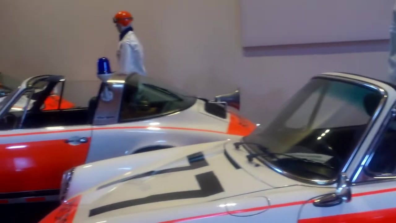 Porsche 911 Targa's van de Rijkspolitie met zwaailicht en oranje striping in een automuseum