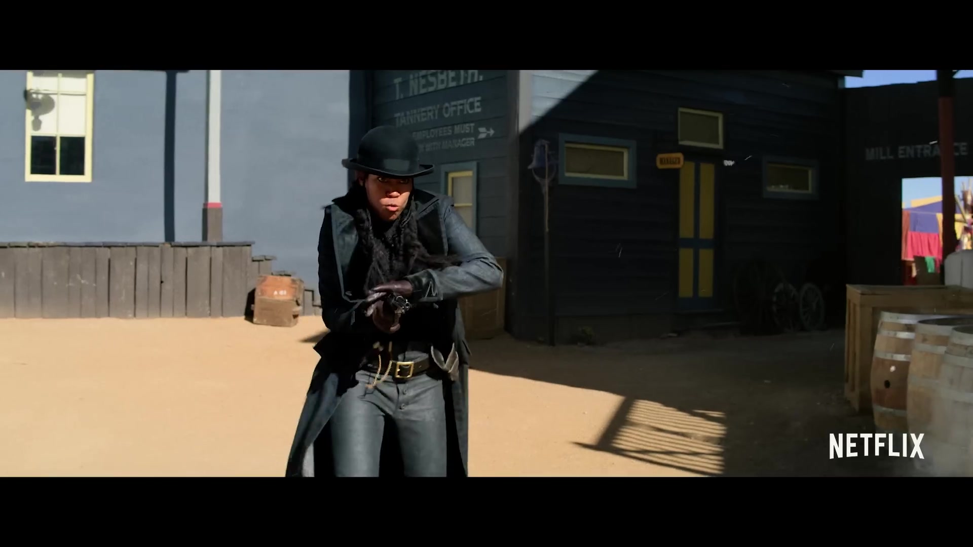 Revolverheld in een lange jas en bolhoed in een westernstadje in The Harder They Fall